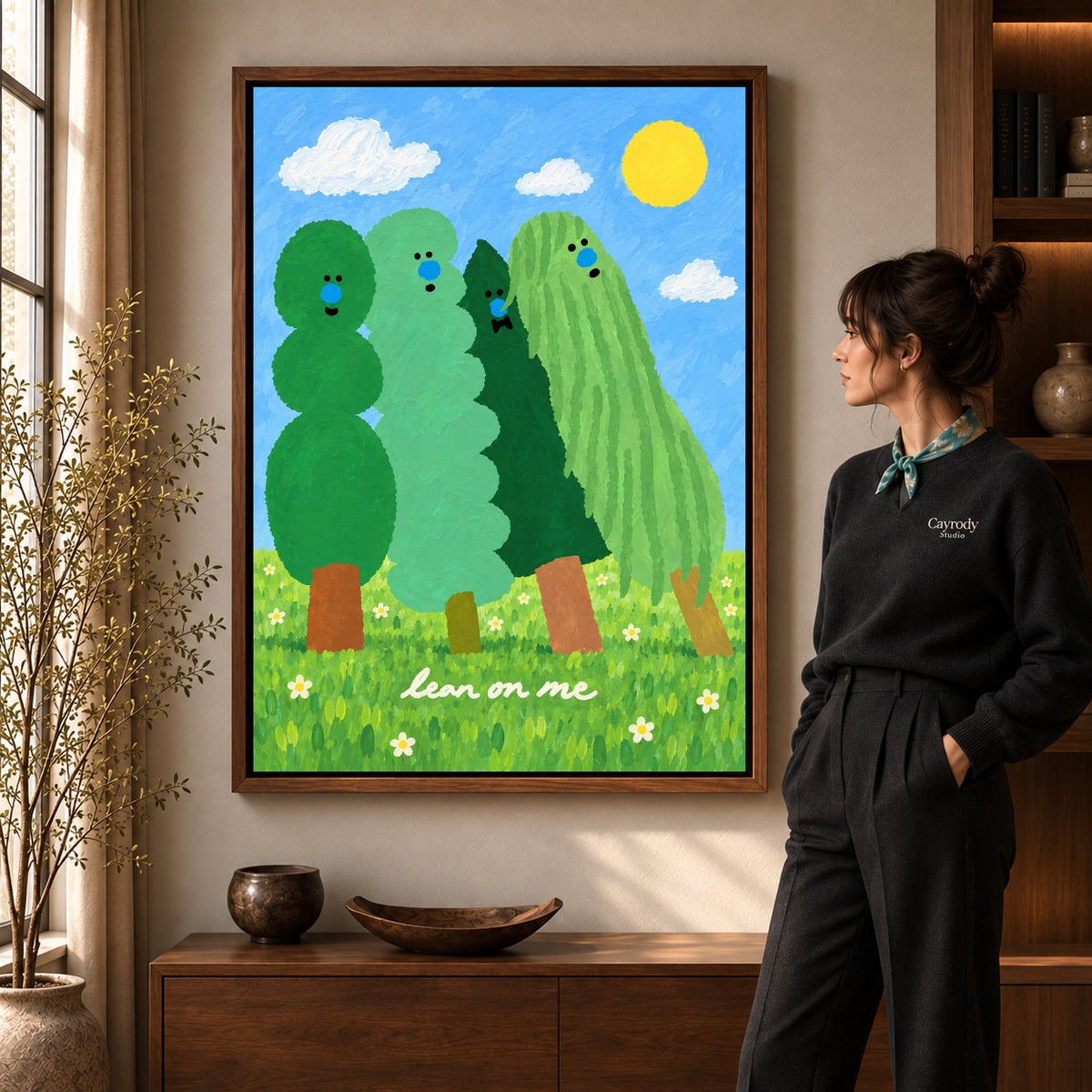 lean on me trees canvas art in a walnut frame beside a standing woman and wooden console.