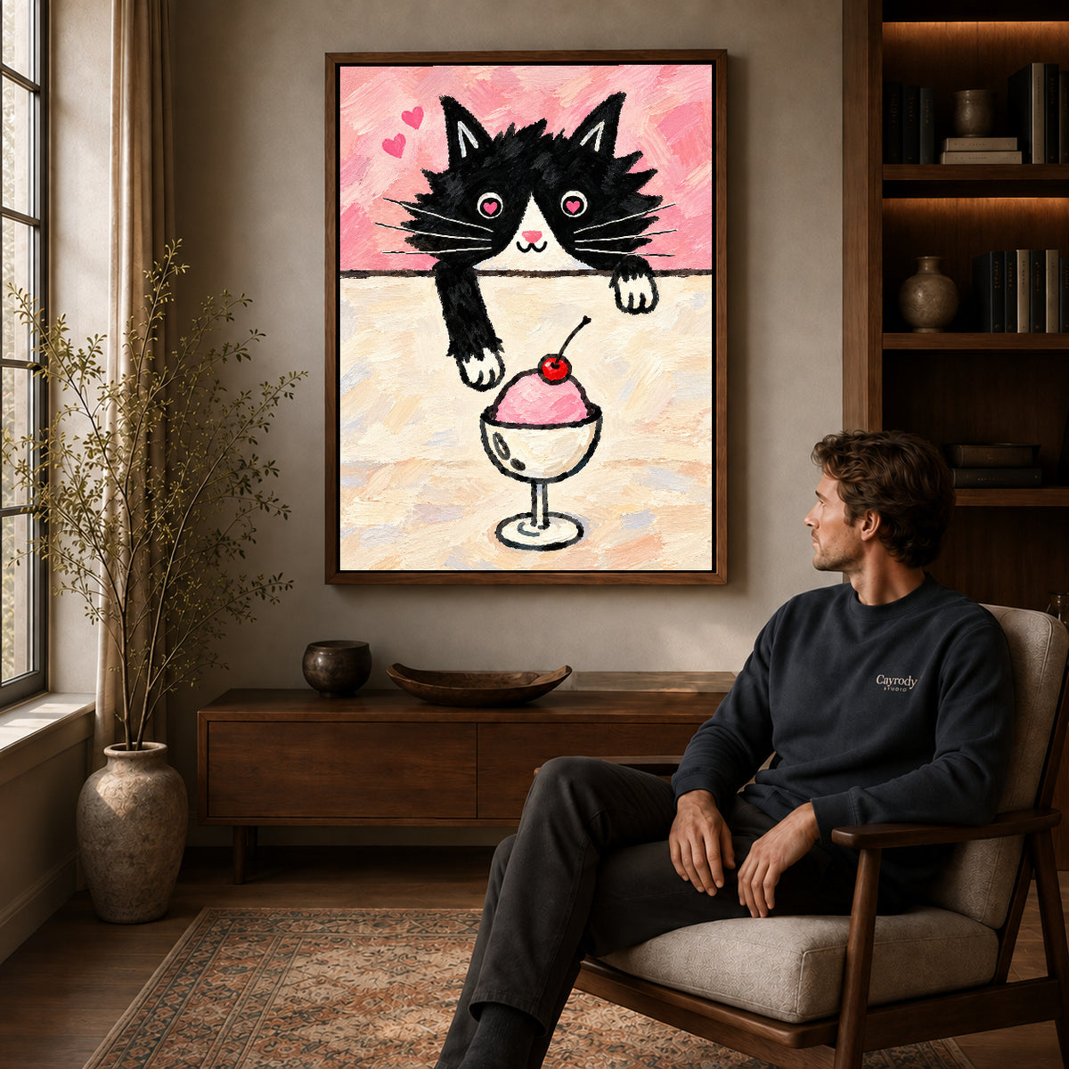 ice cream cat canvas art in a walnut frame above a console beside a seated man.