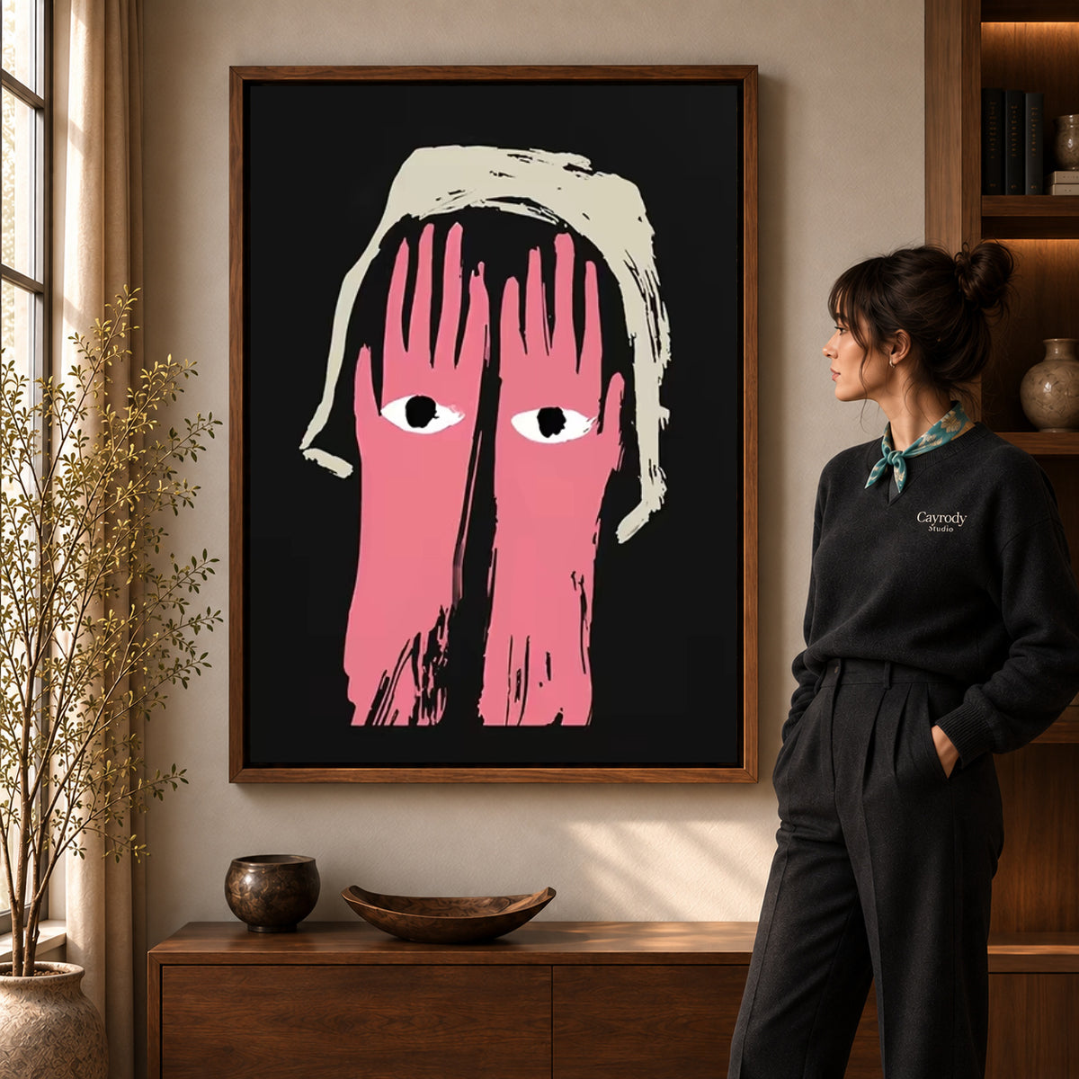pink hands watch canvas art in a walnut frame beside a standing woman and wooden console.