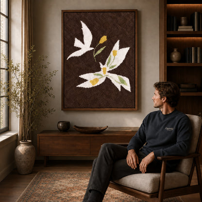 doves golden flowers canvas art in a walnut frame above a console beside a seated man.