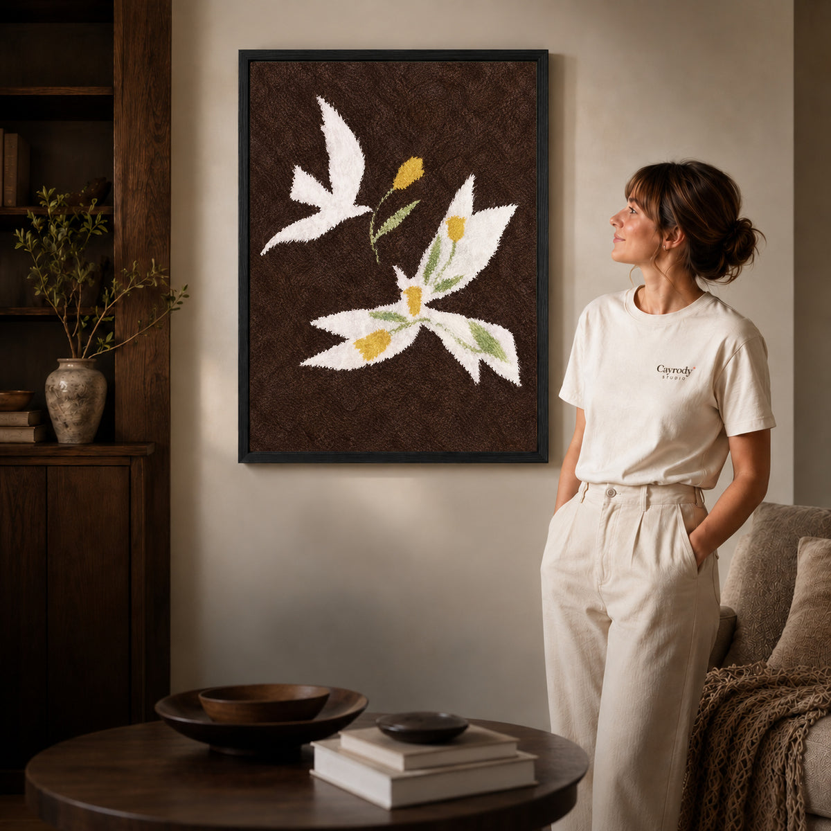 doves golden flowers canvas art in a black frame beside a woman and round wooden table.