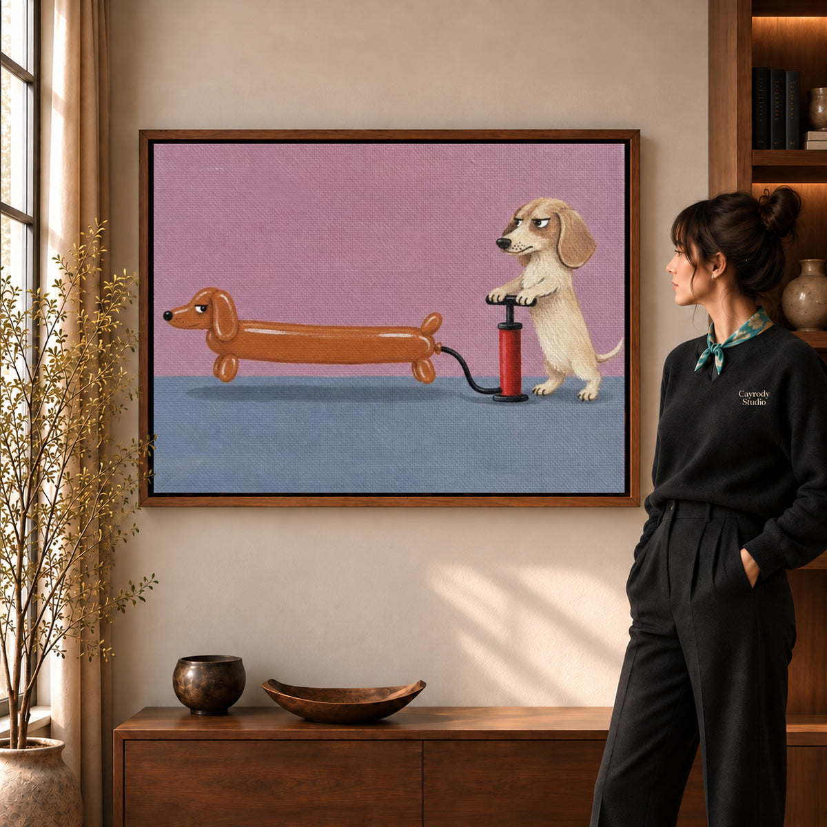 Dachshund balloon canvas art in a walnut frame beside a standing woman in a warm living room.