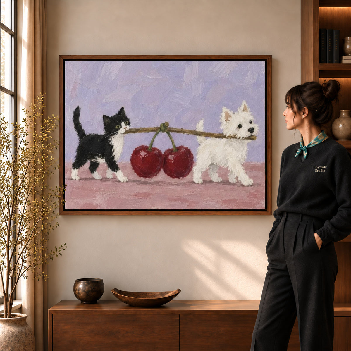 Cherry carrying pets canvas art in a walnut frame beside a standing woman in a warm living room.