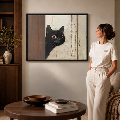 Black framed peeking black cat canvas art displayed beside a woman in a warm neutral living room.