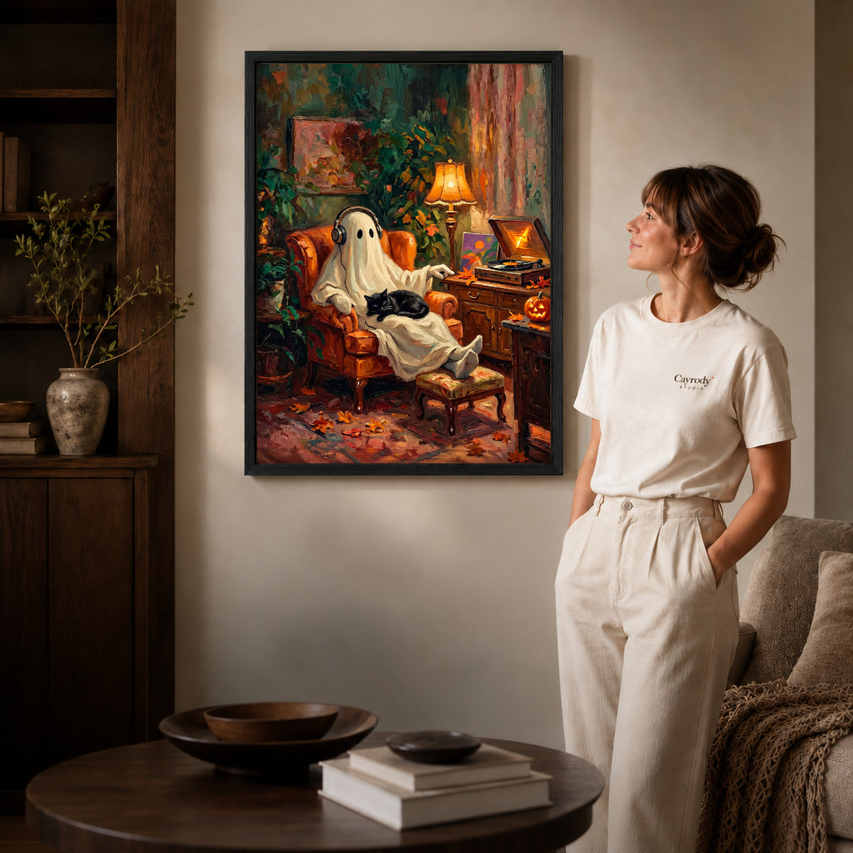 Black framed ghost music canvas art displayed beside a woman in a warm neutral living room.