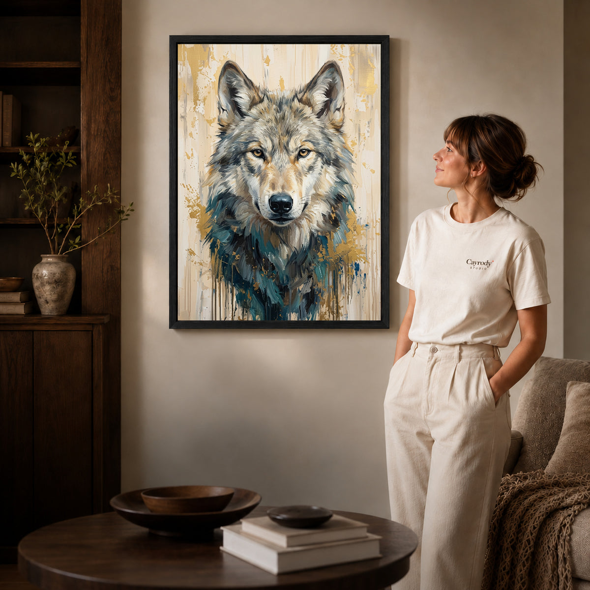Black framed gray wolf portrait canvas art displayed beside a woman in a warm neutral living room.