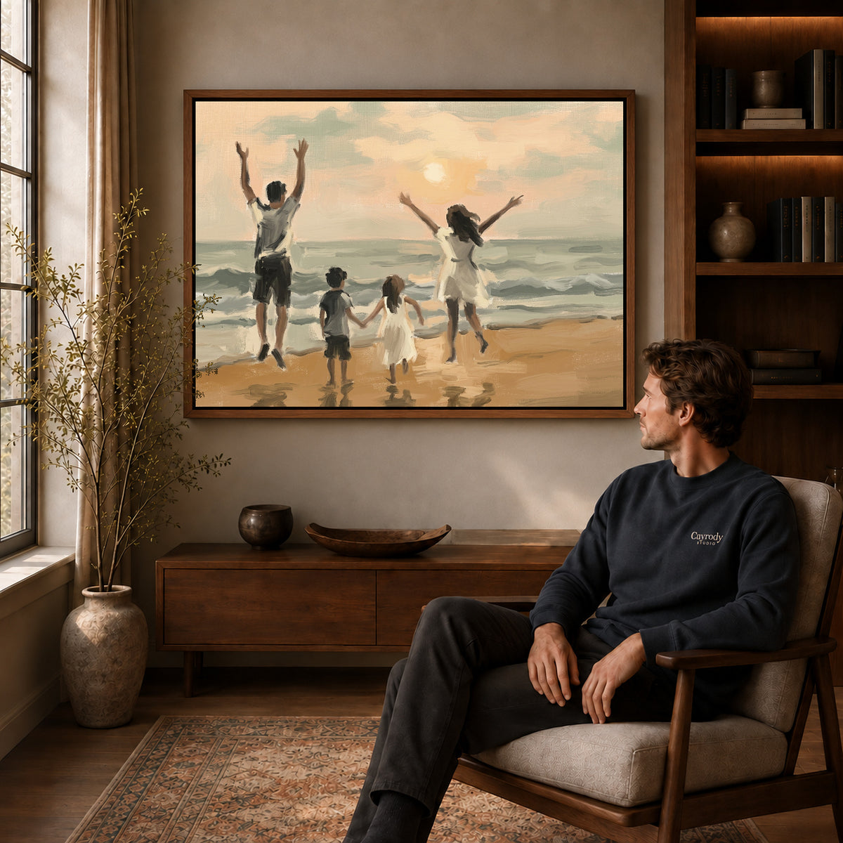 Walnut framed family beach sunset canvas art displayed above a seated man in a wood furnished room.