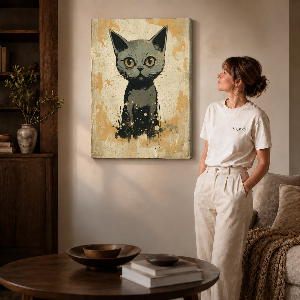 Gallery wrapped golden eyed kitten canvas art with naturally shaded canvas edges beside a woman wearing cream clothing.