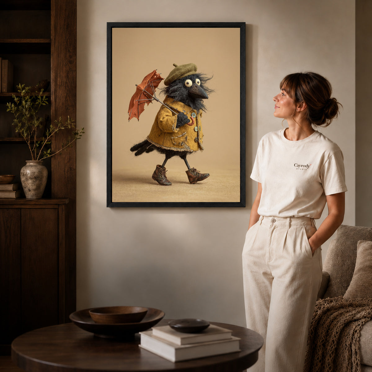 Black framed umbrella crow canvas art displayed beside a woman in a warm neutral living room.