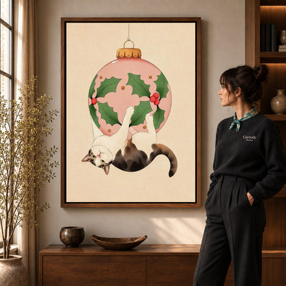Hanging holiday cat canvas art in a walnut frame beside a standing woman in a warm living room.