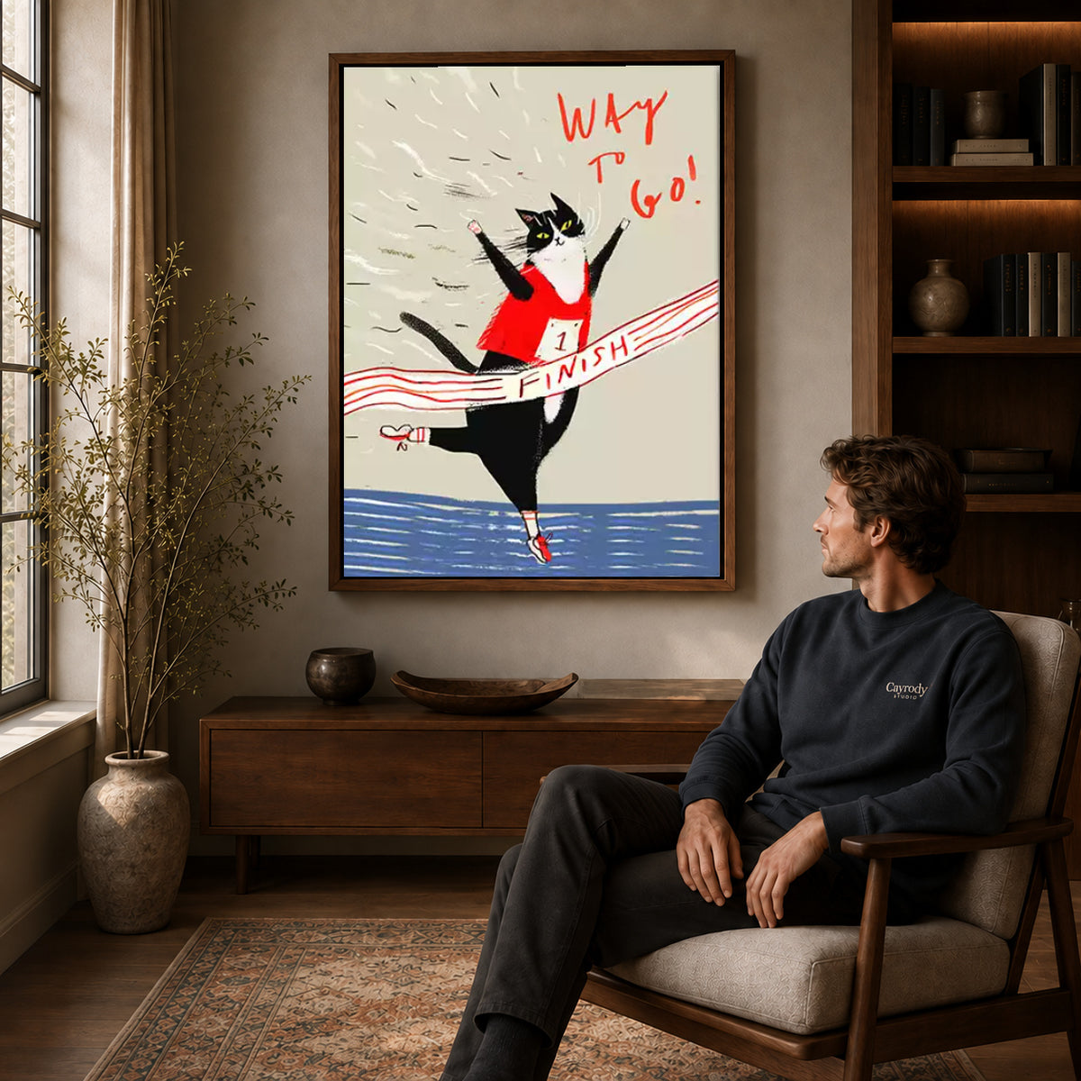 Walnut framed running cat canvas art displayed above a seated man in a wood furnished living room.