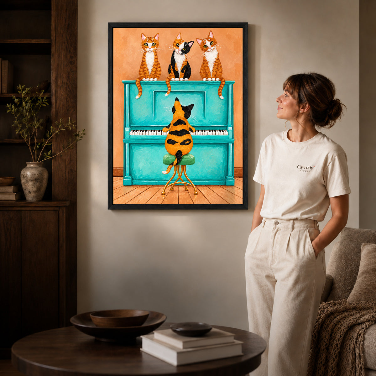 Black framed cat piano quartet canvas art displayed beside a woman in a warm neutral living room.