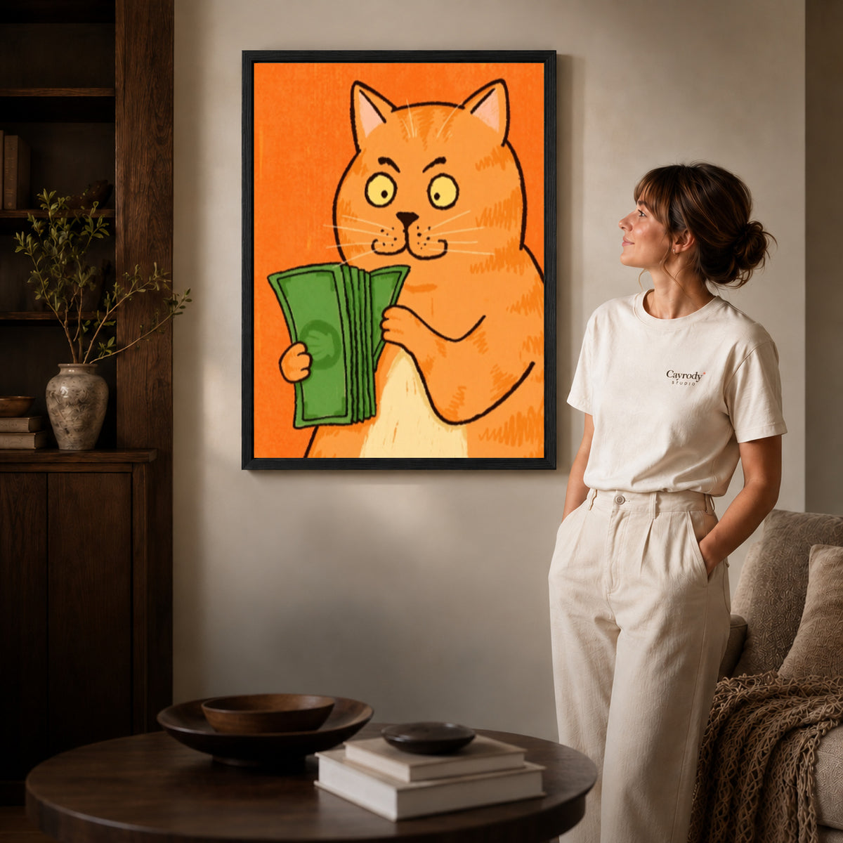 Black framed money cat portrait canvas art displayed beside a woman in a warm neutral living room.