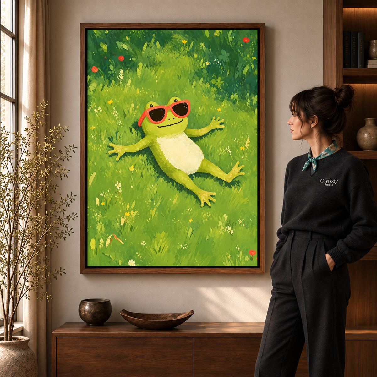 Relaxed sunny frog canvas art in a walnut frame beside a standing woman in a warm living room.