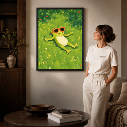 Black framed relaxed sunny frog canvas art displayed beside a woman in a warm neutral living room.