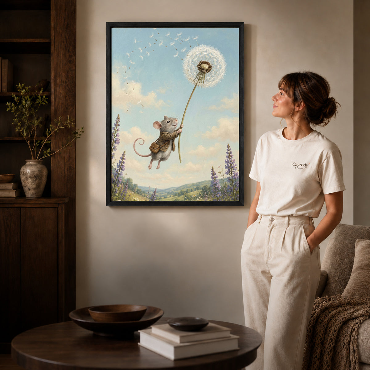 Black framed dandelion mouse ride canvas art displayed beside a woman in a warm neutral living room.