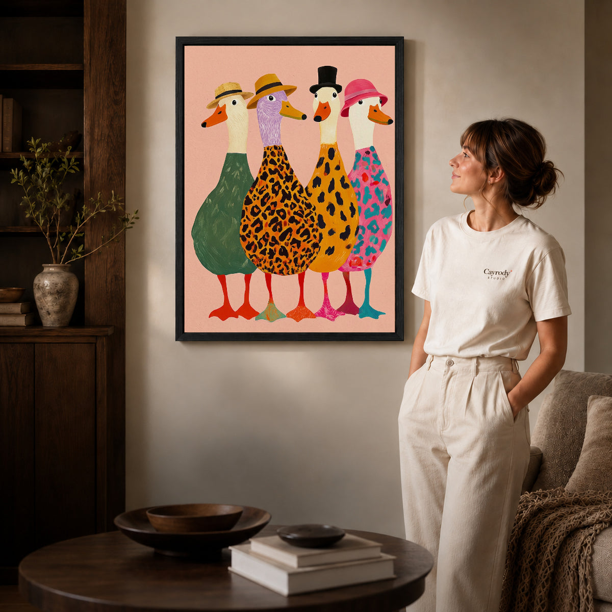 Black framed fashionable goose flock canvas art displayed beside a woman in a warm neutral living room.
