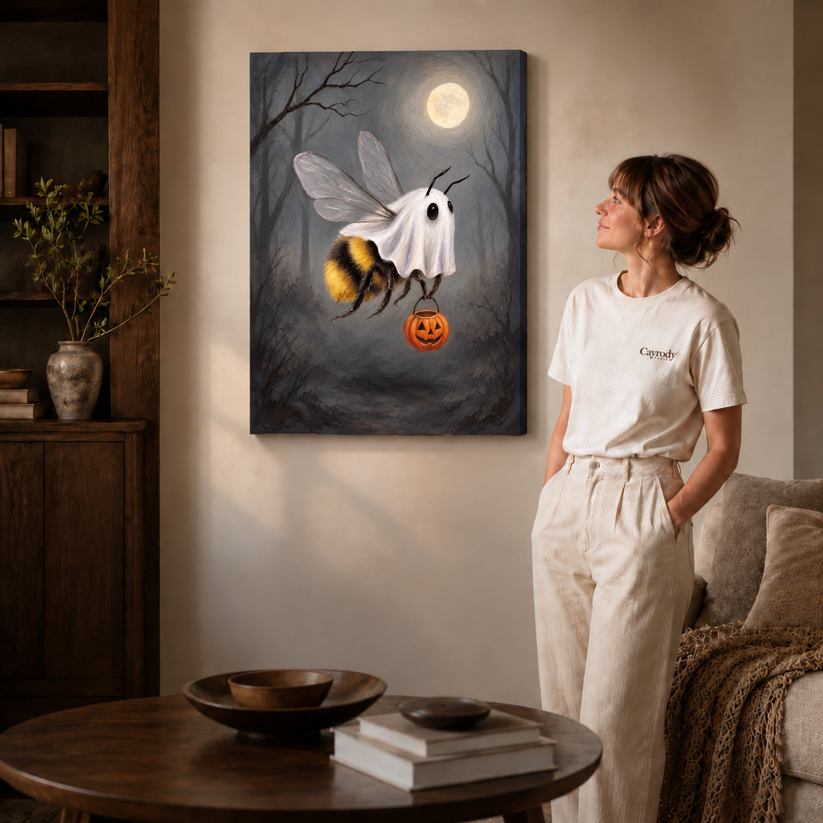 Gallery wrapped ghost costume bee canvas art with naturally shaded canvas edges beside a woman wearing cream clothing.