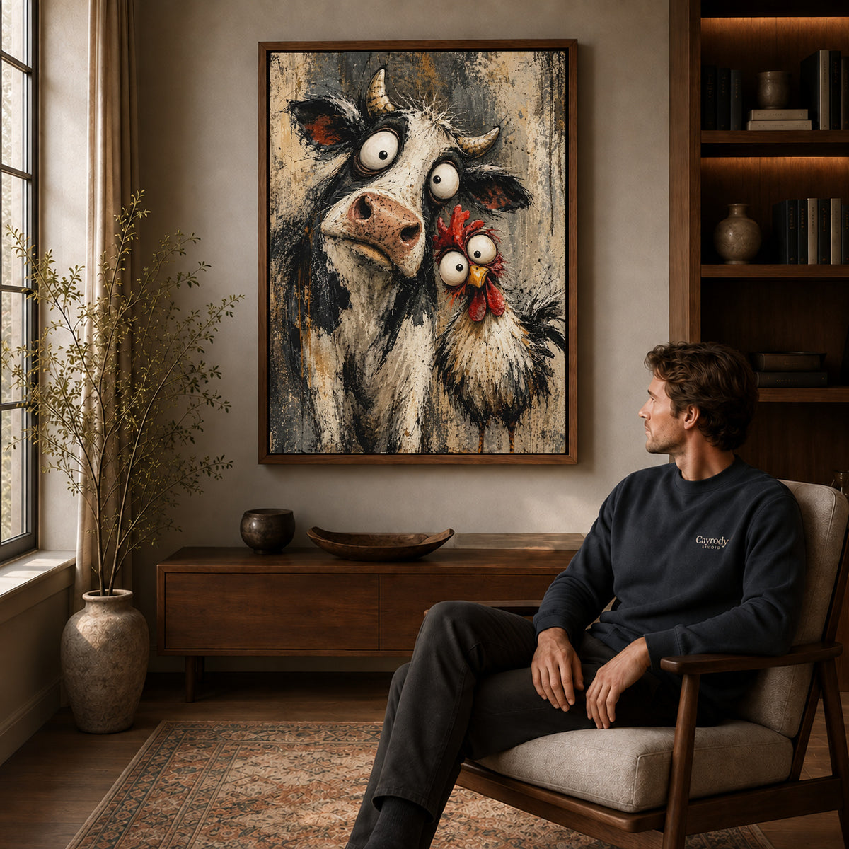 Walnut framed cow chicken friends canvas art displayed above a seated man in a wood furnished room.