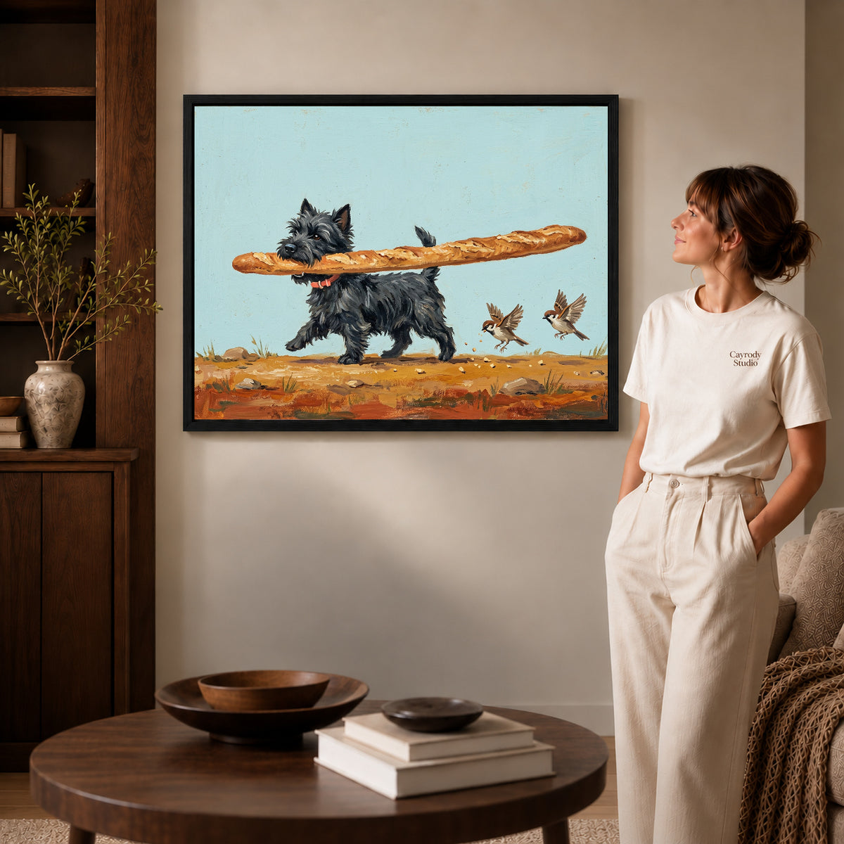 Black framed baguette terrier canvas art displayed beside a woman in a warm neutral living room.
