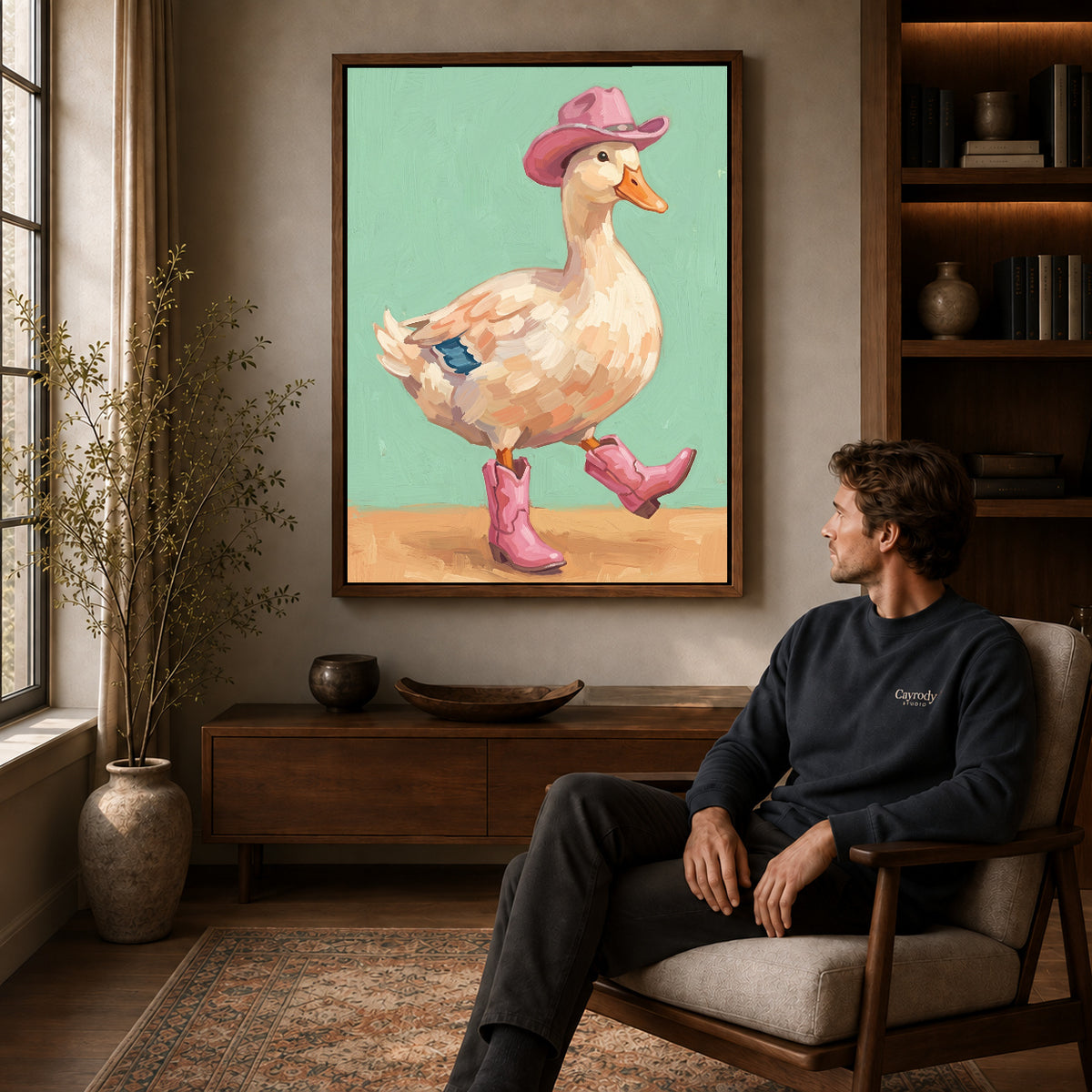 Walnut framed cowboy boots duck canvas art displayed above a seated man in a wood furnished room.