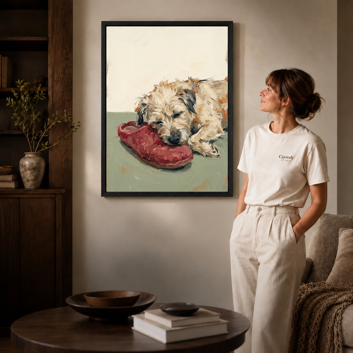 Black framed sleeping dog shoe canvas art displayed beside a woman in a warm neutral living room.