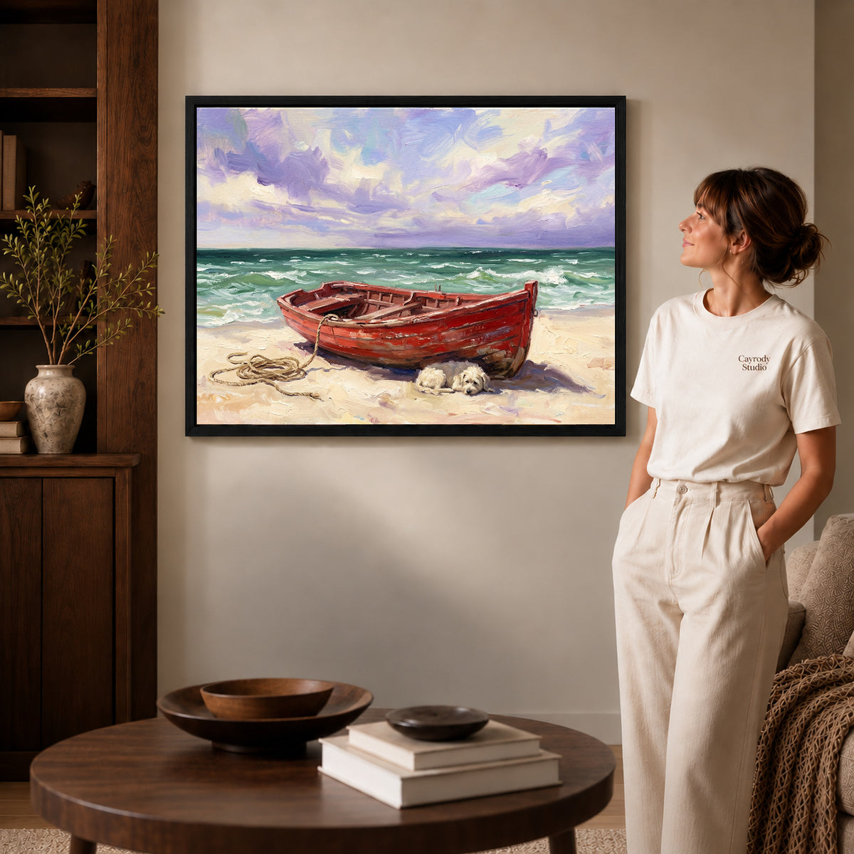 Black framed red boat beach canvas art displayed beside a woman in a warm neutral living room.
