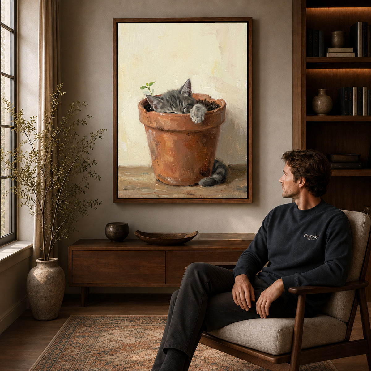 Walnut framed sleeping kitten pot canvas art displayed above a seated man in a wood furnished room.