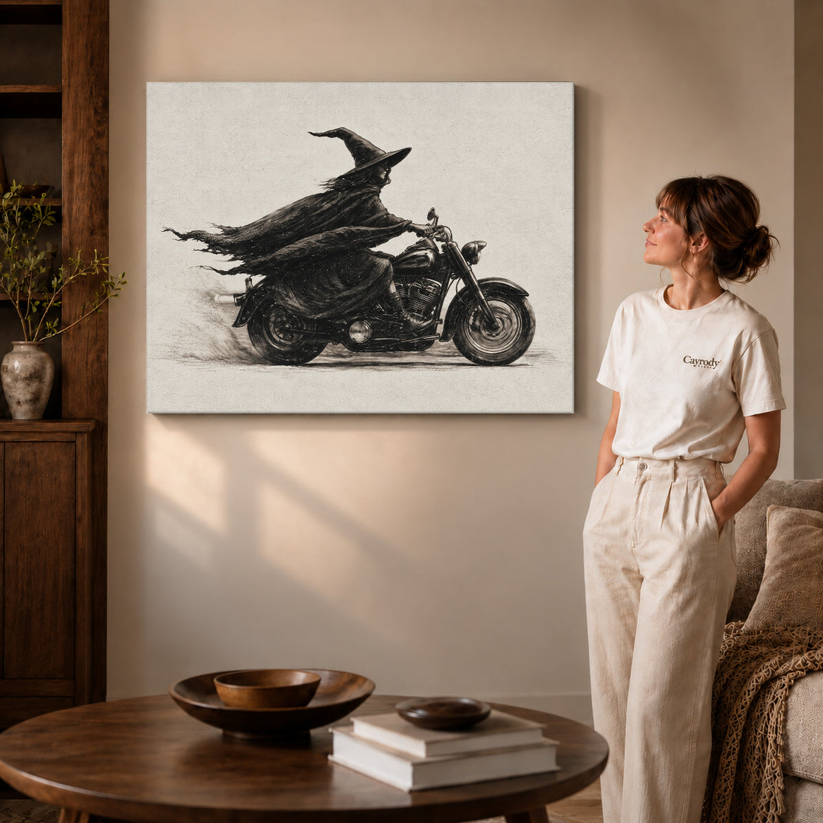 Gallery wrapped midnight witch rider artwork with shaded canvas edges beside a woman wearing cream clothing.