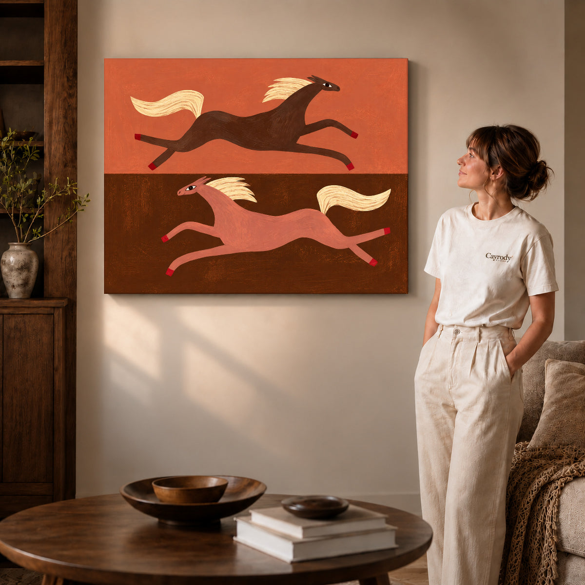 Gallery wrapped opposite galloping horses artwork with shaded canvas edges beside a woman wearing cream clothing.