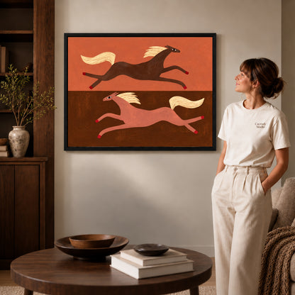 Black framed opposite galloping horses artwork beside a woman in a warm neutral living room.
