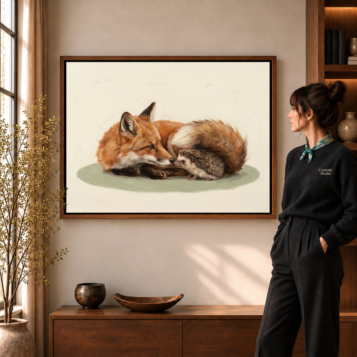Fox hedgehog friends canvas art in a walnut frame beside a standing woman in a warm living room.