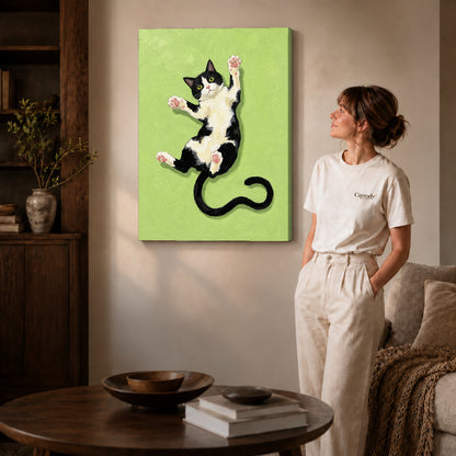 Gallery wrapped stretching tuxedo cat canvas art with naturally shaded canvas edges beside a woman wearing cream clothing.