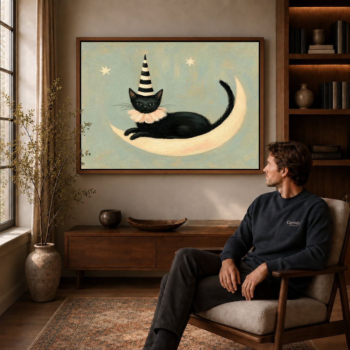 Walnut framed crescent lounging cat artwork above a seated man in a wood furnished living room.