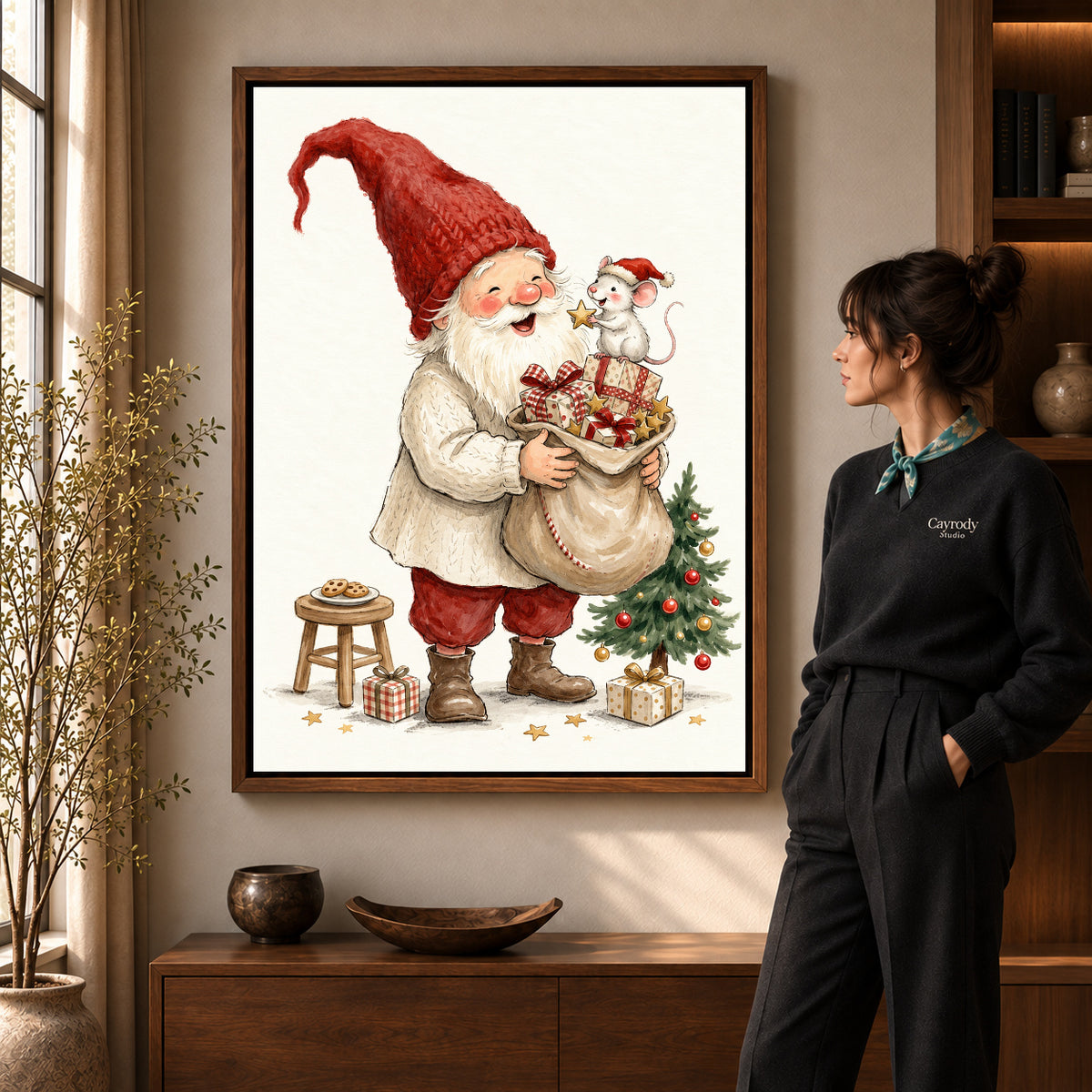 Santa Mouse Surprise artwork in a walnut frame beside a standing woman in a warm room.