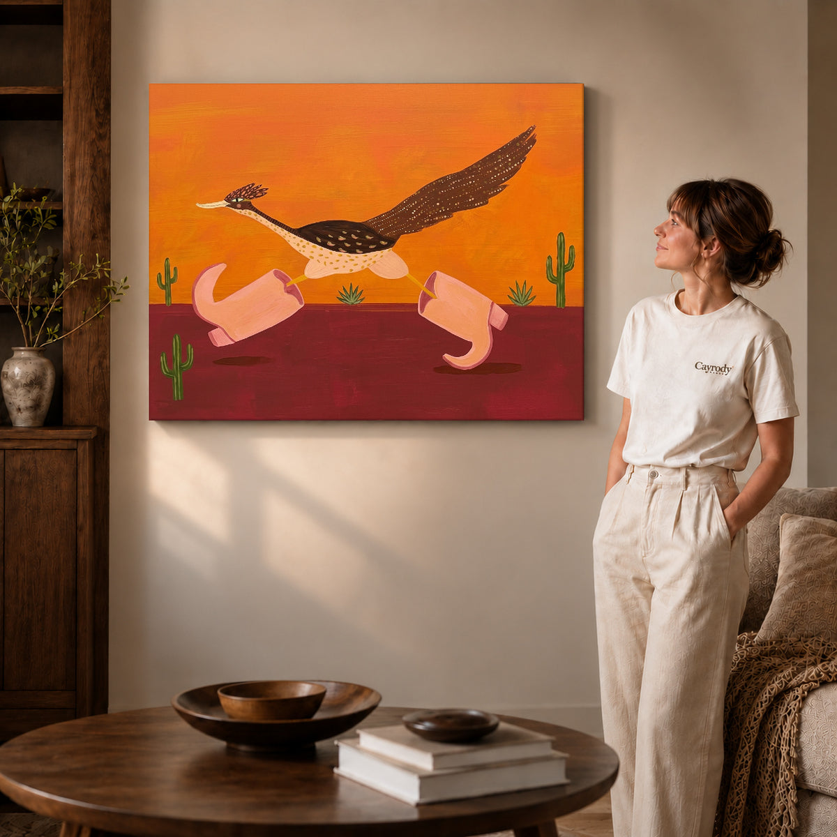 Gallery wrapped folk roadrunner pink boots canvas art with naturally shaded canvas edges beside a woman wearing cream clothing.