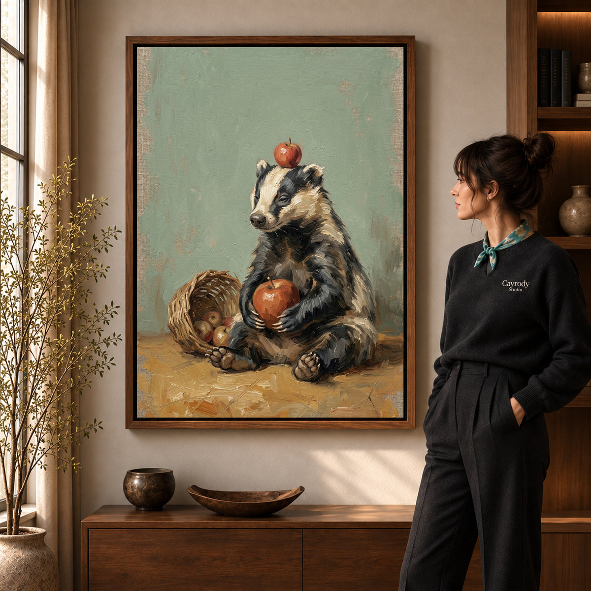 Badger apple basket canvas art in a walnut frame beside a standing woman in a warm living room.