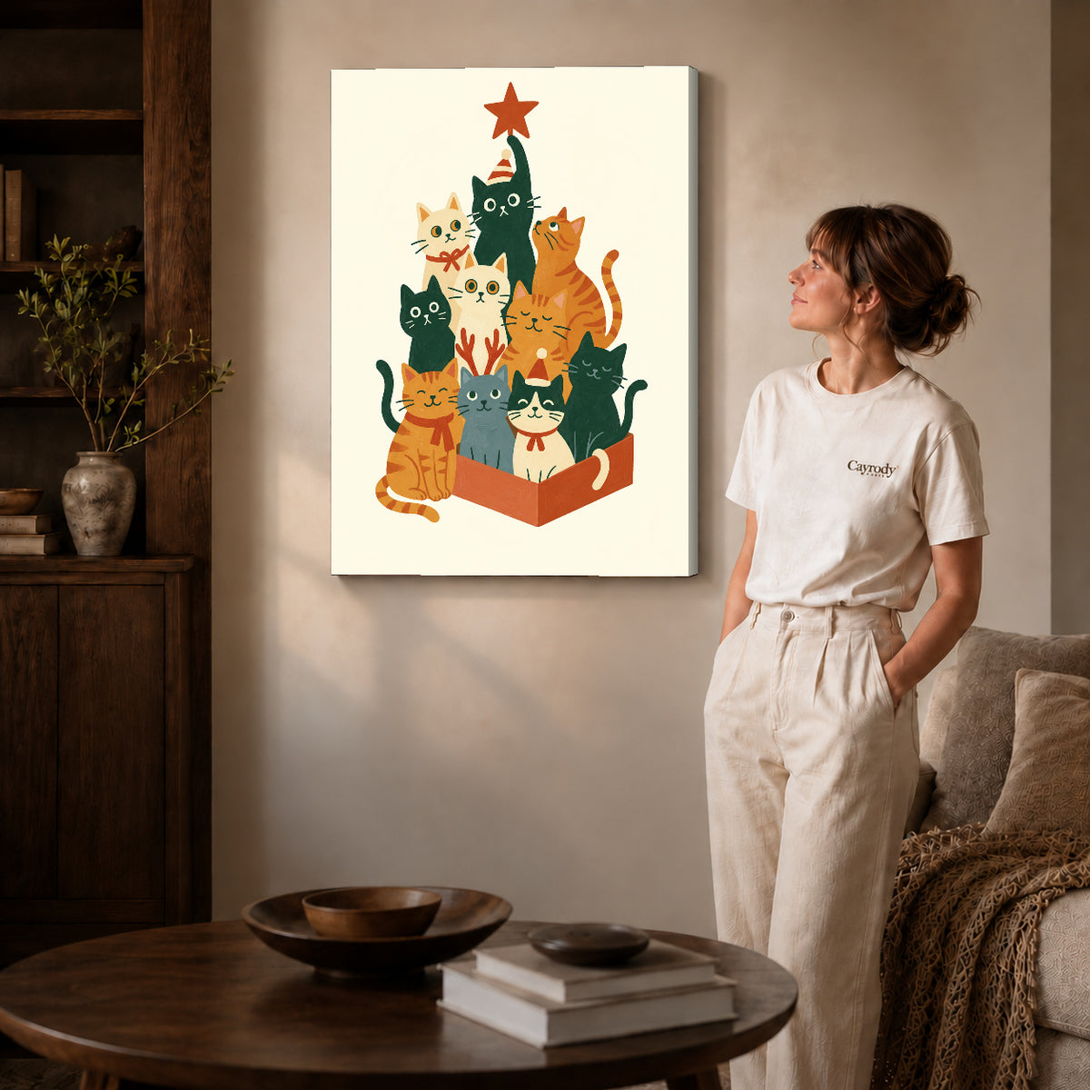 Gallery wrapped christmas cat gathering artwork with shaded canvas edges beside a woman wearing cream clothing.