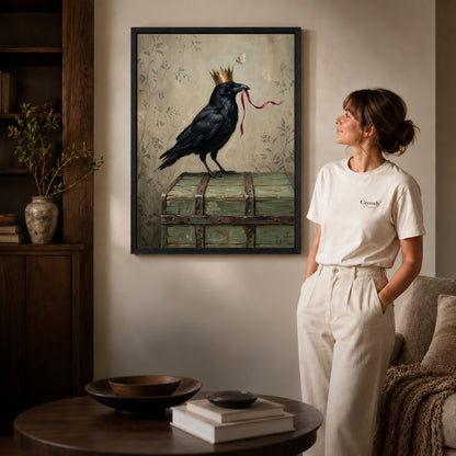 Black framed crowned raven ribbon canvas art displayed beside a woman in a warm neutral living room.