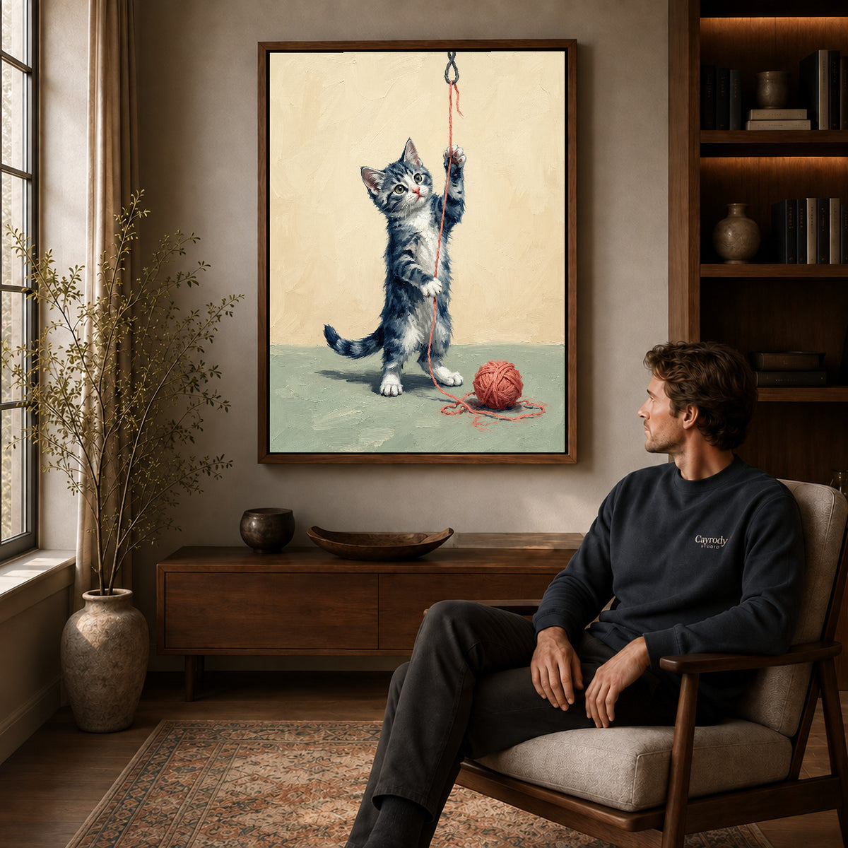 Walnut framed playful yarn kitten artwork above a seated man in a wood furnished living room.