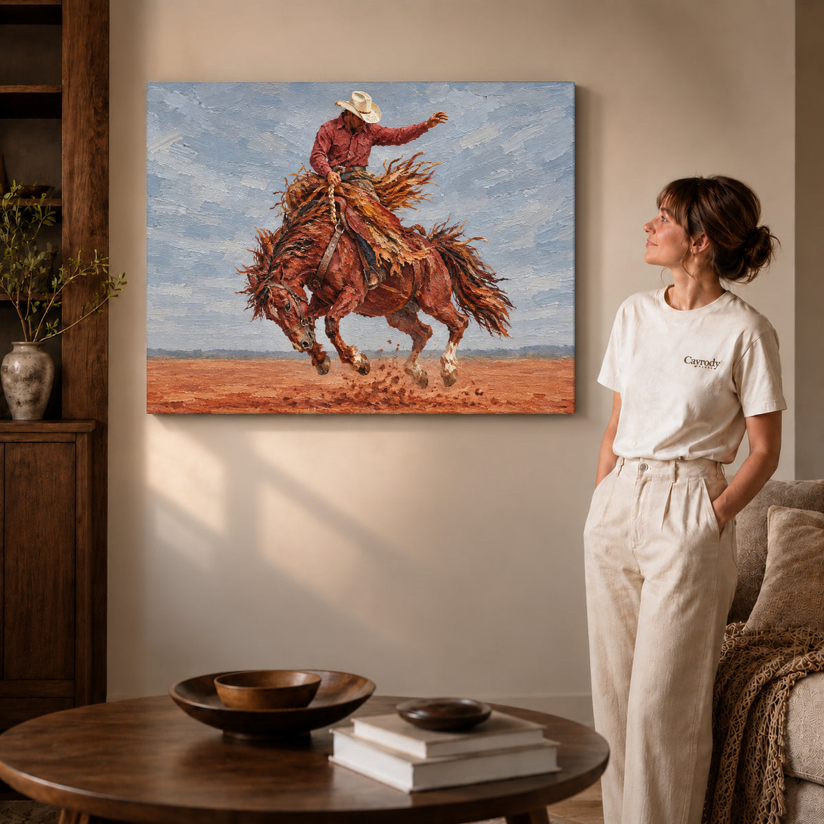 Gallery wrapped bucking horse rider artwork with shaded canvas edges beside a woman wearing cream clothing.