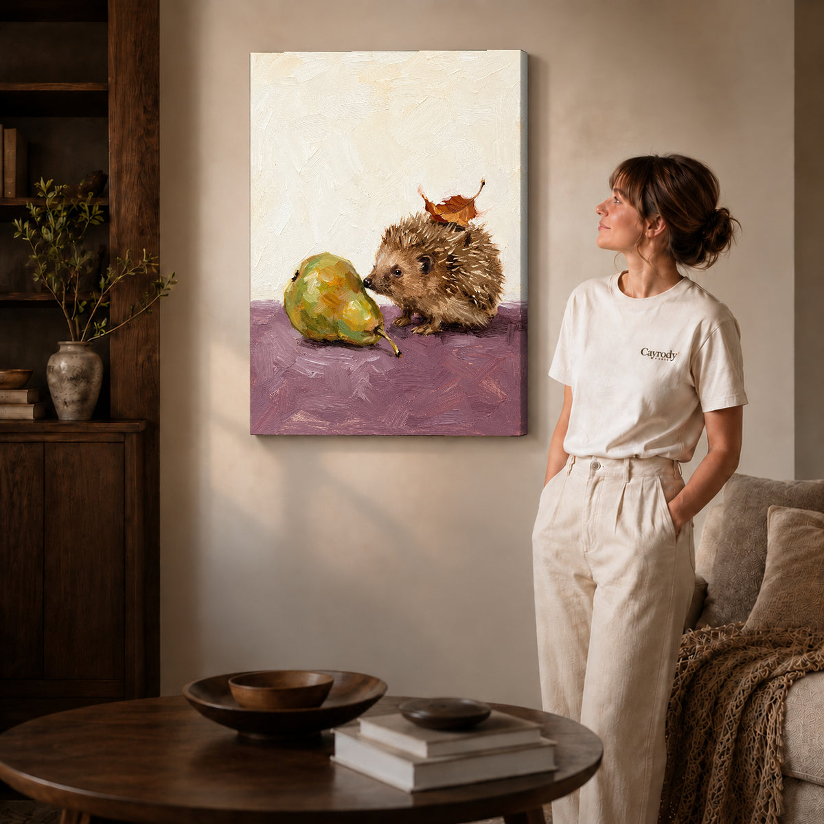 Gallery wrapped hedgehog and pear artwork with shaded canvas edges beside a woman wearing cream clothing.