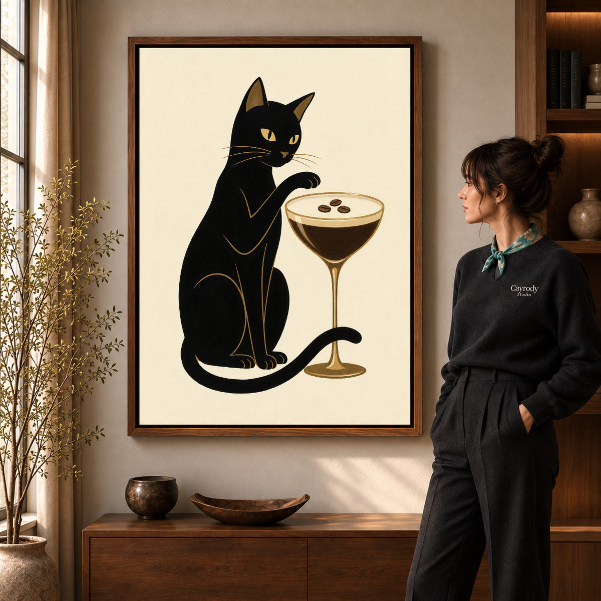 Espresso Martini Cat artwork in a walnut frame beside a standing woman in a warm room.