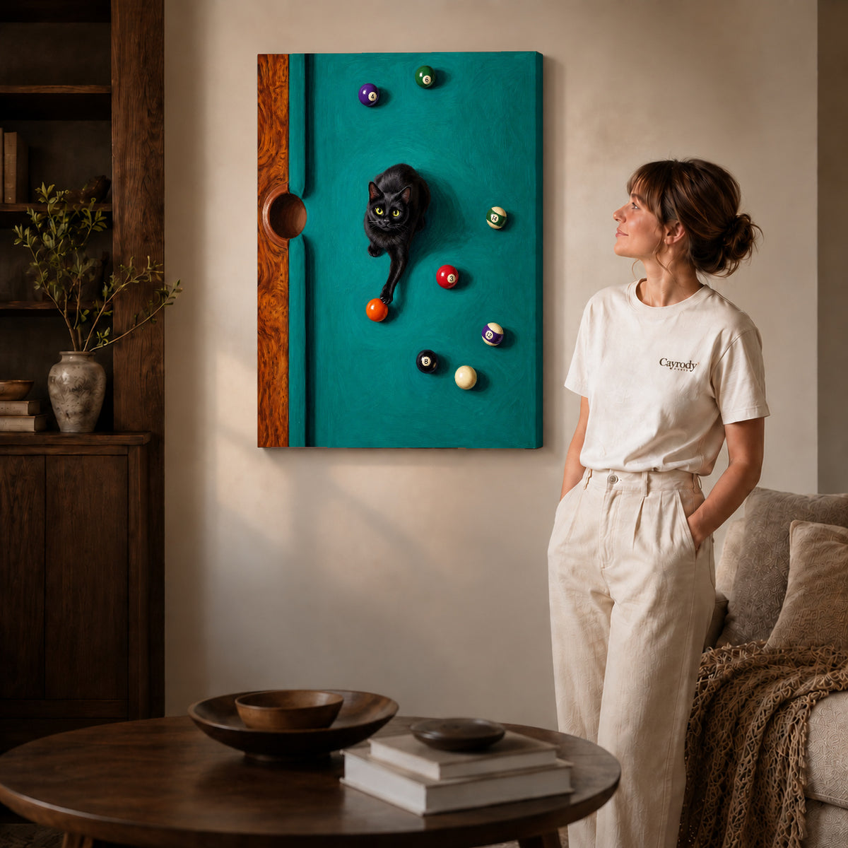 Gallery wrapped playful billiard cat artwork with shaded canvas edges beside a woman wearing cream clothing.