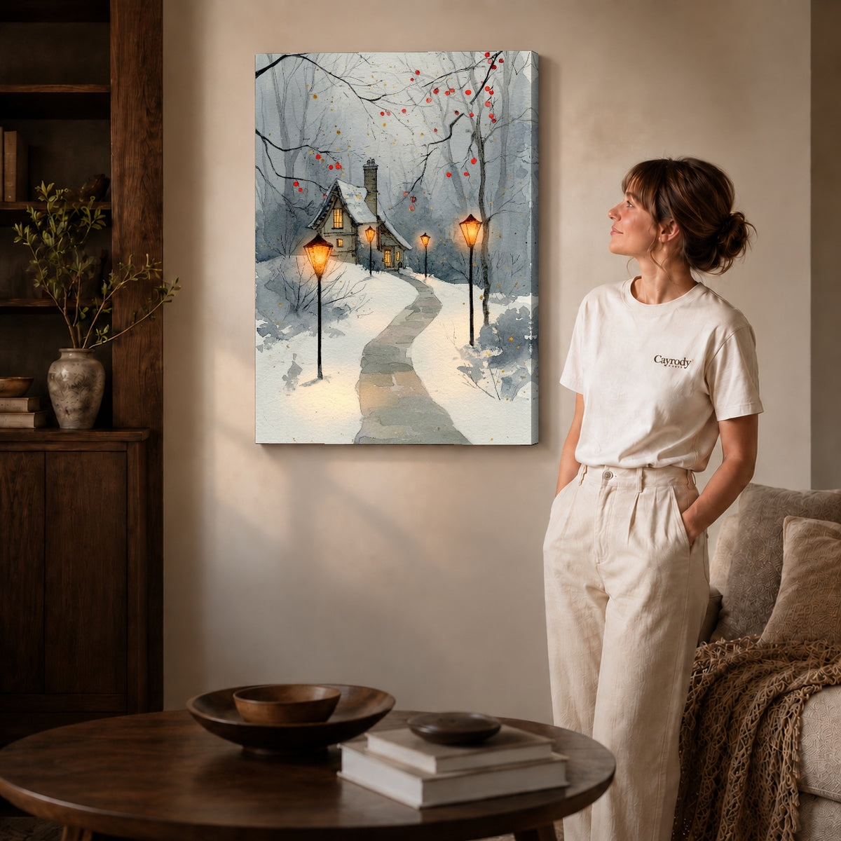 Gallery wrapped snowy cottage lights artwork with shaded canvas edges beside a woman wearing cream clothing.