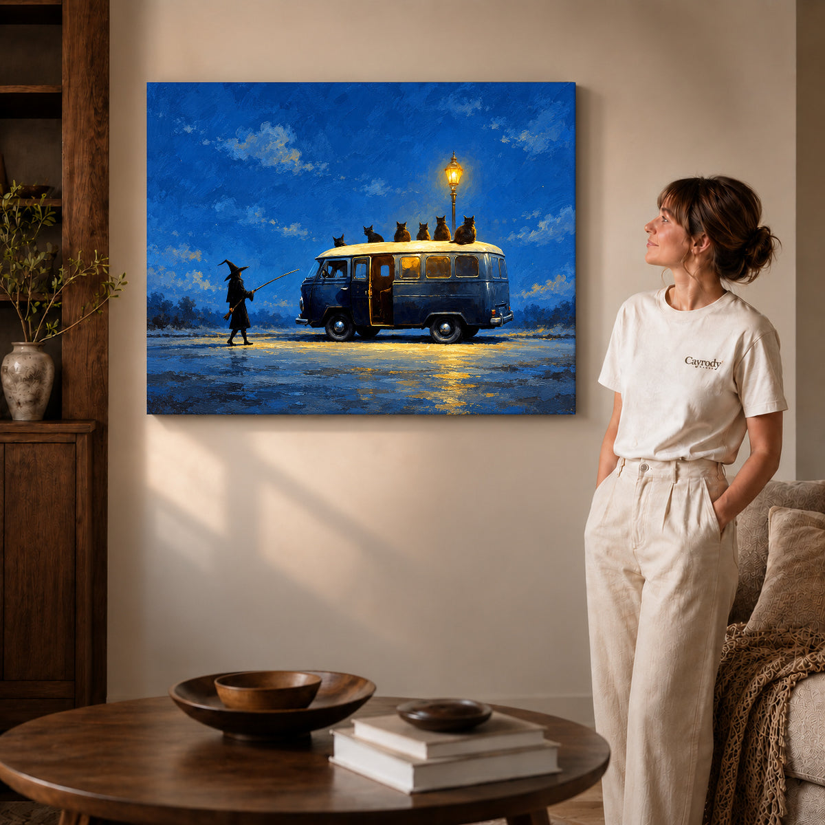 Gallery wrapped witch cat van artwork with shaded canvas edges beside a woman wearing cream clothing.