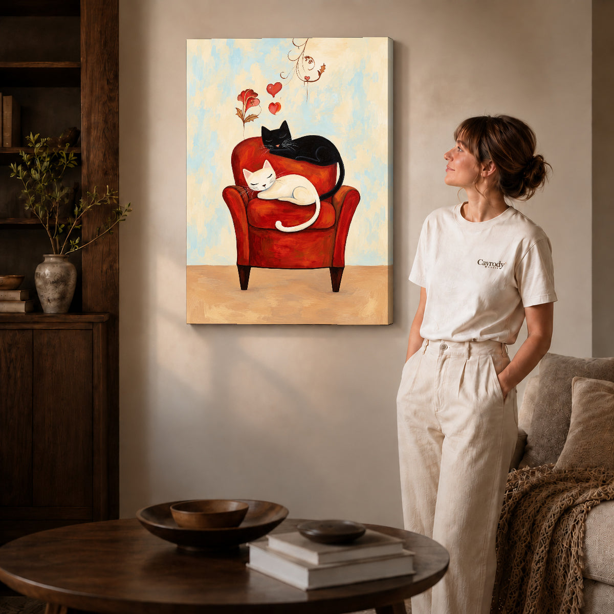 Gallery wrapped sleeping armchair cats artwork with shaded canvas edges beside a woman wearing cream clothing.