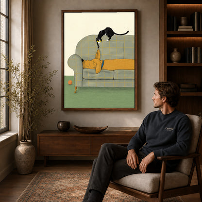 Walnut framed mischievous sofa kitten artwork above a seated man in a wood furnished living room.