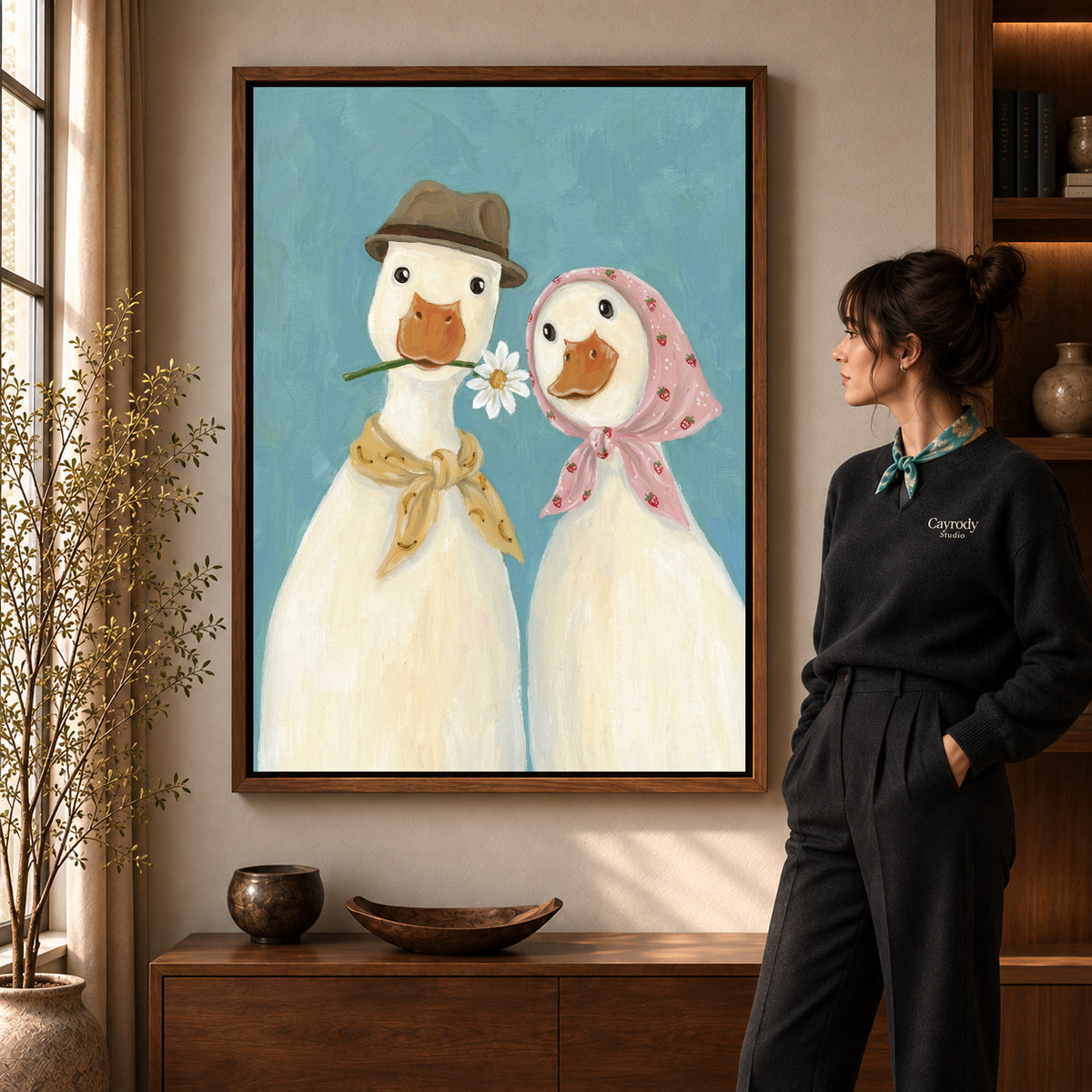 Daisy Duck Couple artwork in a walnut frame beside a standing woman in a warm room.