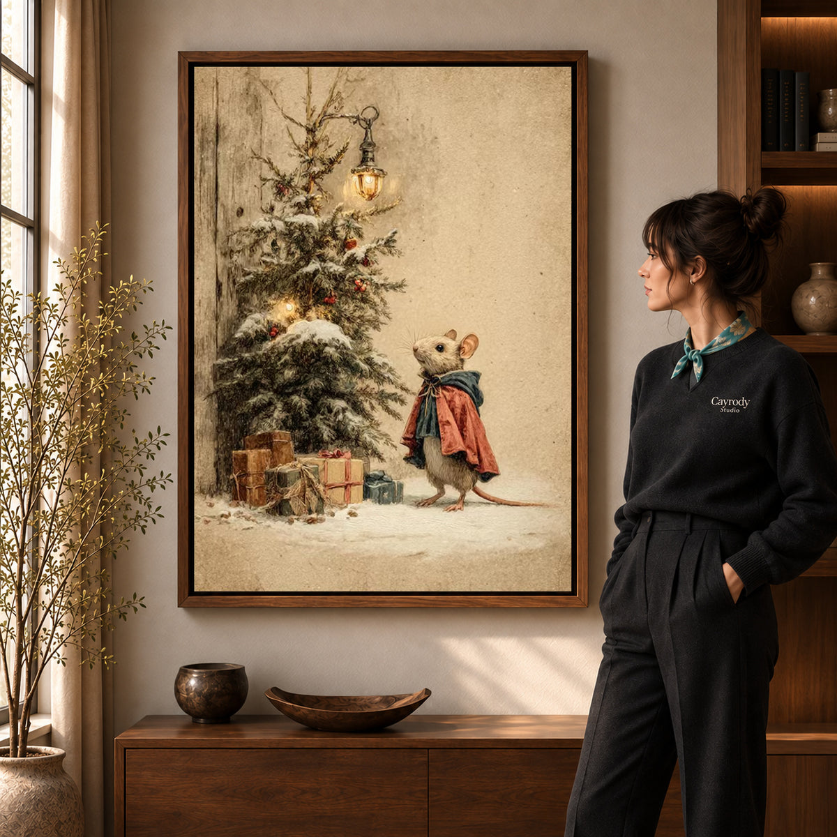 Christmas Mouse Visit artwork in a walnut frame beside a standing woman in a warm room.